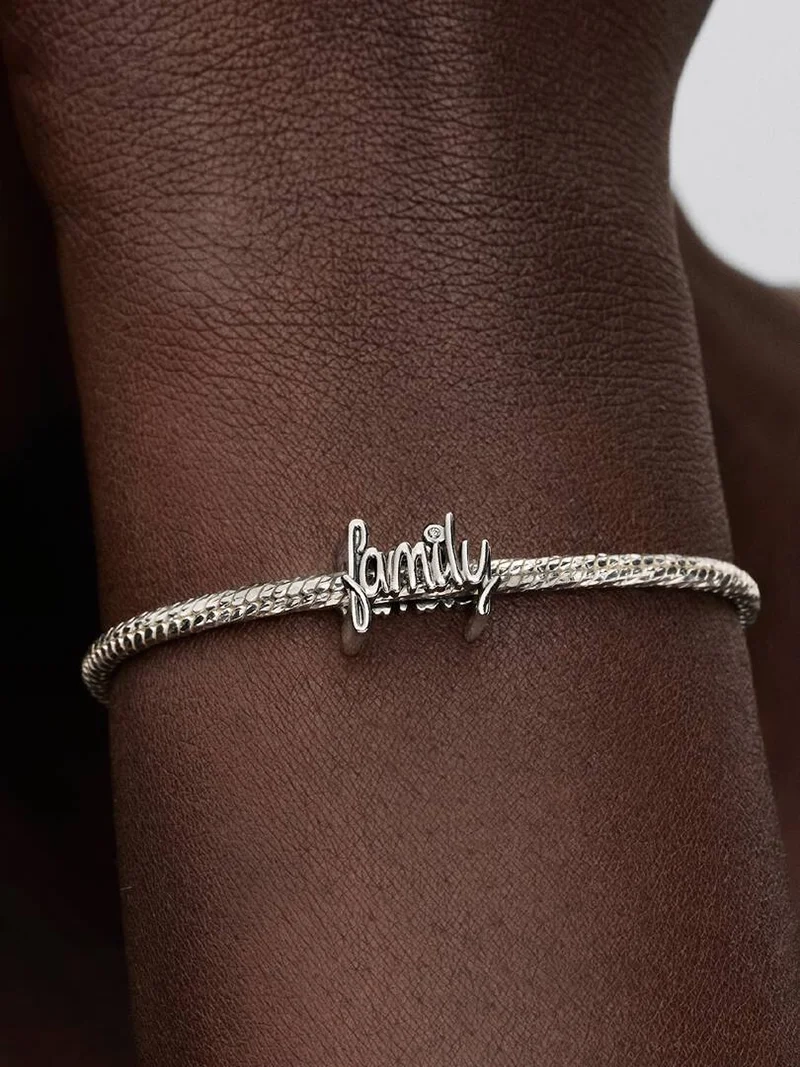 jossa on käsin kirjoitettu sana "family" ja kimalteleva kuutiollinen zirkonia "i"-kirjaimen yläpuolella. Rakkauden ja yhdessäolon symboli Pandora Moments -mallistosta.