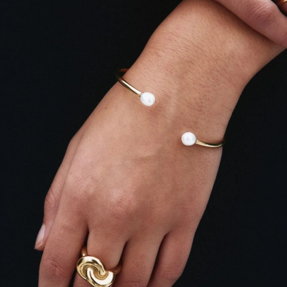Guldfärgat öppet armband med två stora pärlor i ändarna