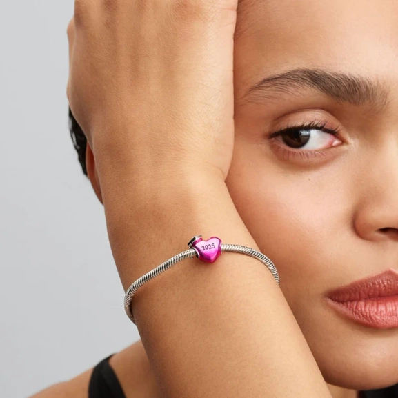 Hjärtformad Examensberlock 2025 från Pandora. En symbol för dina framgångar med examensmössa på rosa emaljerat hjärta i sterlingsilver.