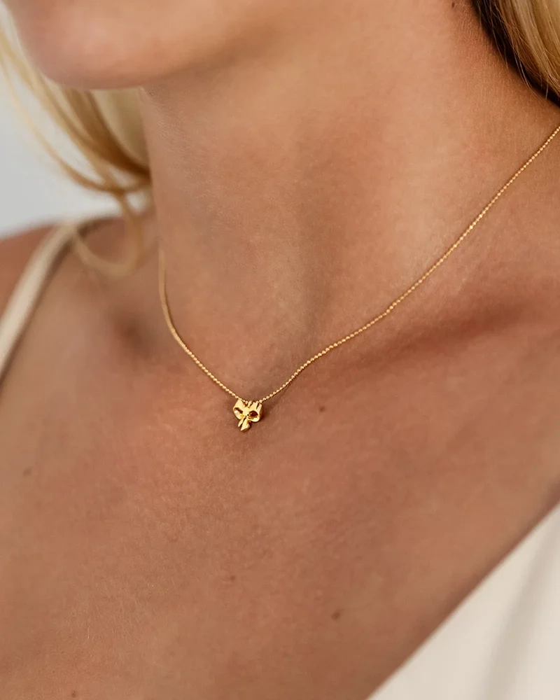 ett elegant halsband i 18K guldpläterat silver med rosettberlock och gnistrande kedja.