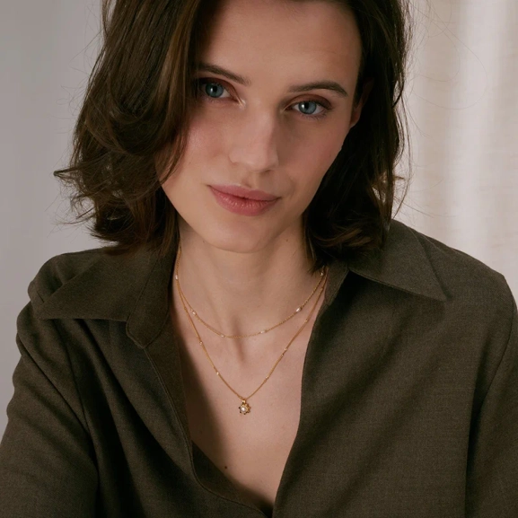 kierretyllä ketjulla ja makeanvedenhelmellä koristellulla kukalla.