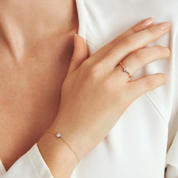 tunn ringskena med rund labbodlad mittdiamant omgiven av mindre diamanter i infattning