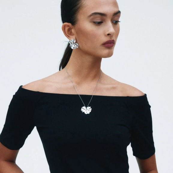 blanka örhängen i rostfritt stål med svepande blombladsform som elegant breder ut sig över örat.