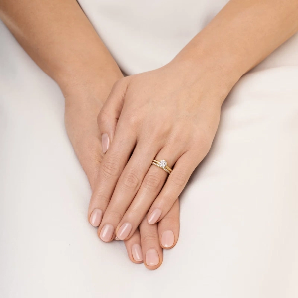ring i 18K gult guld med en stor briljantslipad diamant och mindre pavédiamanter längs skenan.