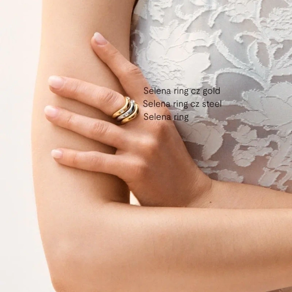 Två Selena ringar i stål och guld med vågformade skenor; en med cubic zirconia-stenar och en slät