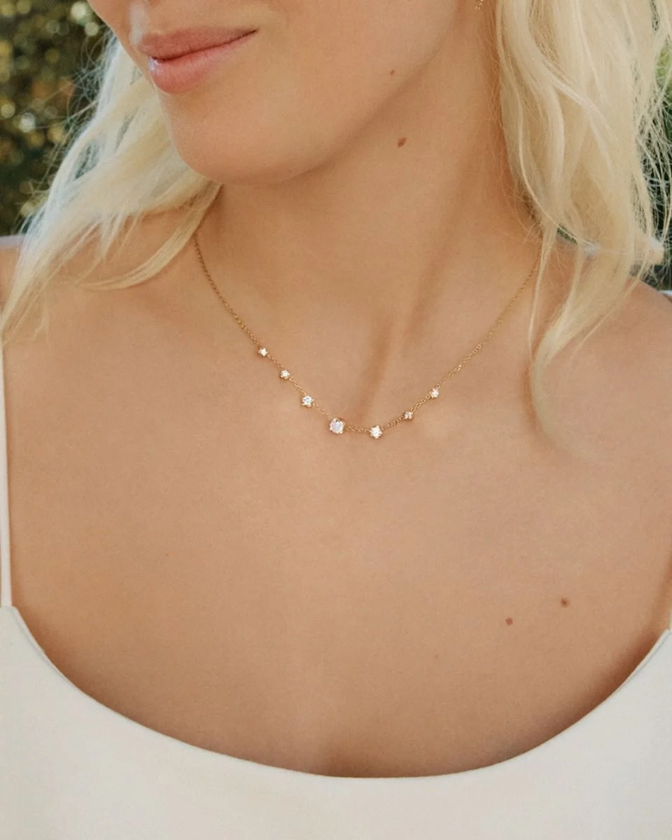 Guldpläterat halsband från Edblad med fyra gnistrande cubic zirconia-stenar i olika storlekar på en tunn kedja.