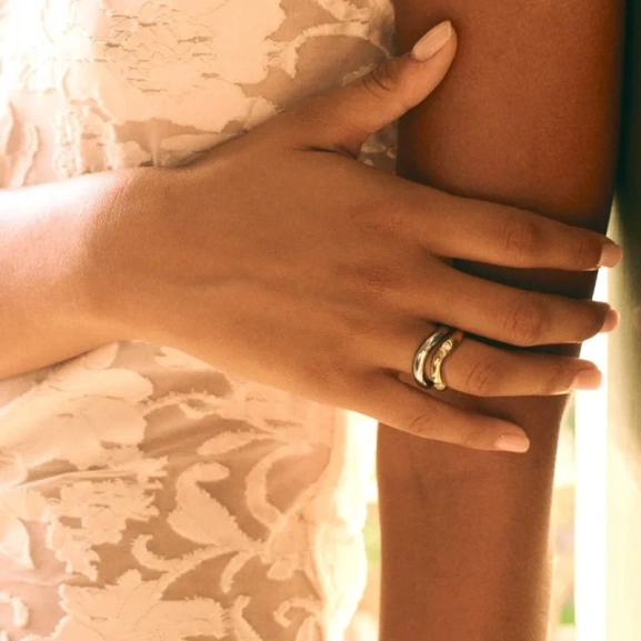 Två släta Selena-ringar i stål och guld med vågformade skenor från Edblad