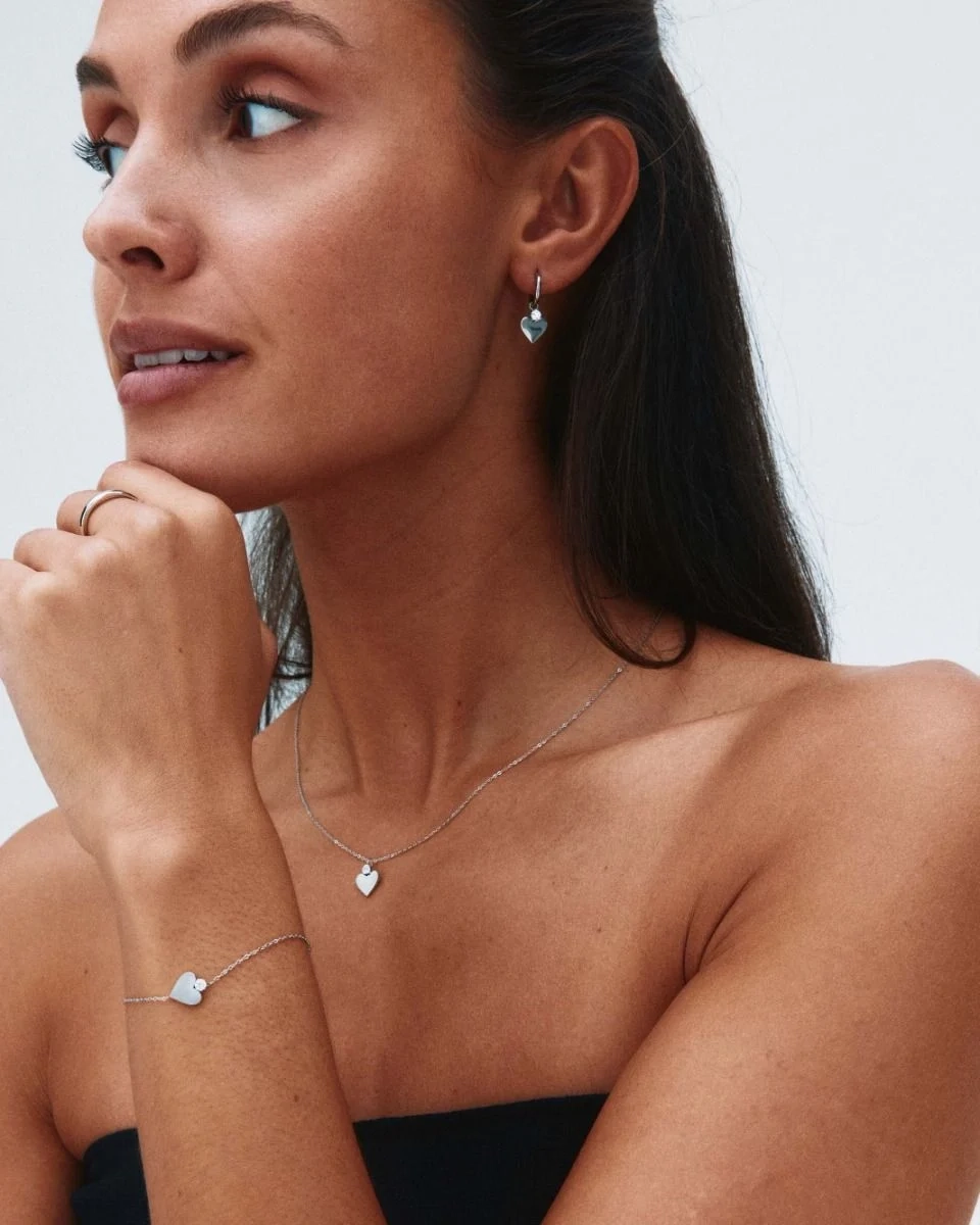 Armband i blankt rostfritt stål med stiliserat hjärta och gnistrande sten på fasettslipad ankarkedja.