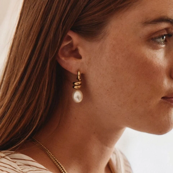 Större studsörhängen i 14K guldplätering med spiralform och oval pärlemorpärla från Edblad Swivel-kollektionen.