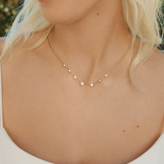 Guldpläterat halsband från Edblad med fyra gnistrande cubic zirconia-stenar i olika storlekar på en tunn kedja.