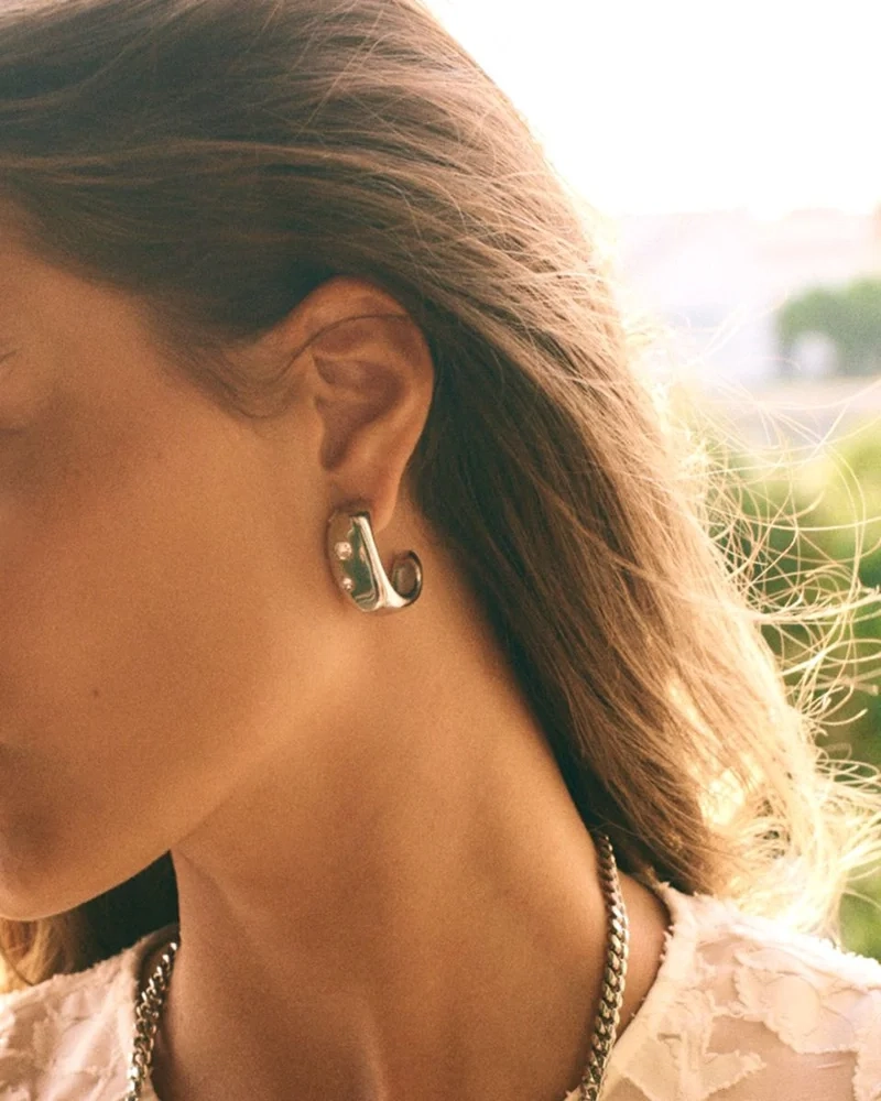 Selena Hoops L i blankt rostfritt stål med oregelbundna ytor och gnistrande cubic zirconia-stenar