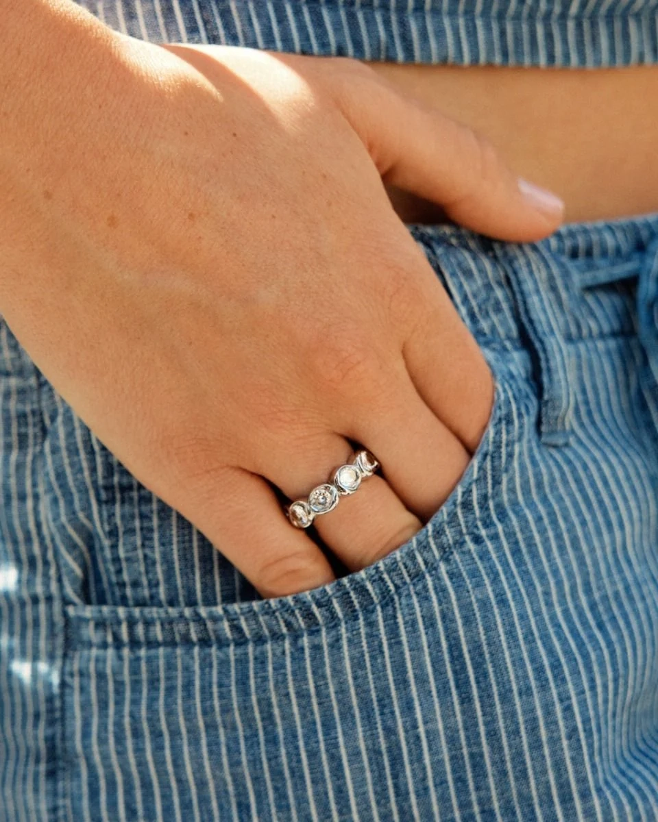 Ring i blankt rostfritt stål med gnistrande stenar runt hela skenan och mjukt rundad insida