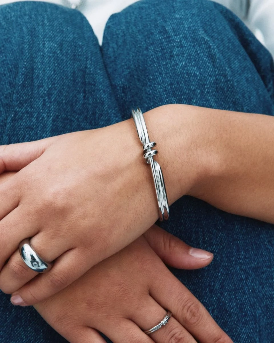 Armband i blankt rostfritt stål med spiralformad detalj och oval pärlemorpärla