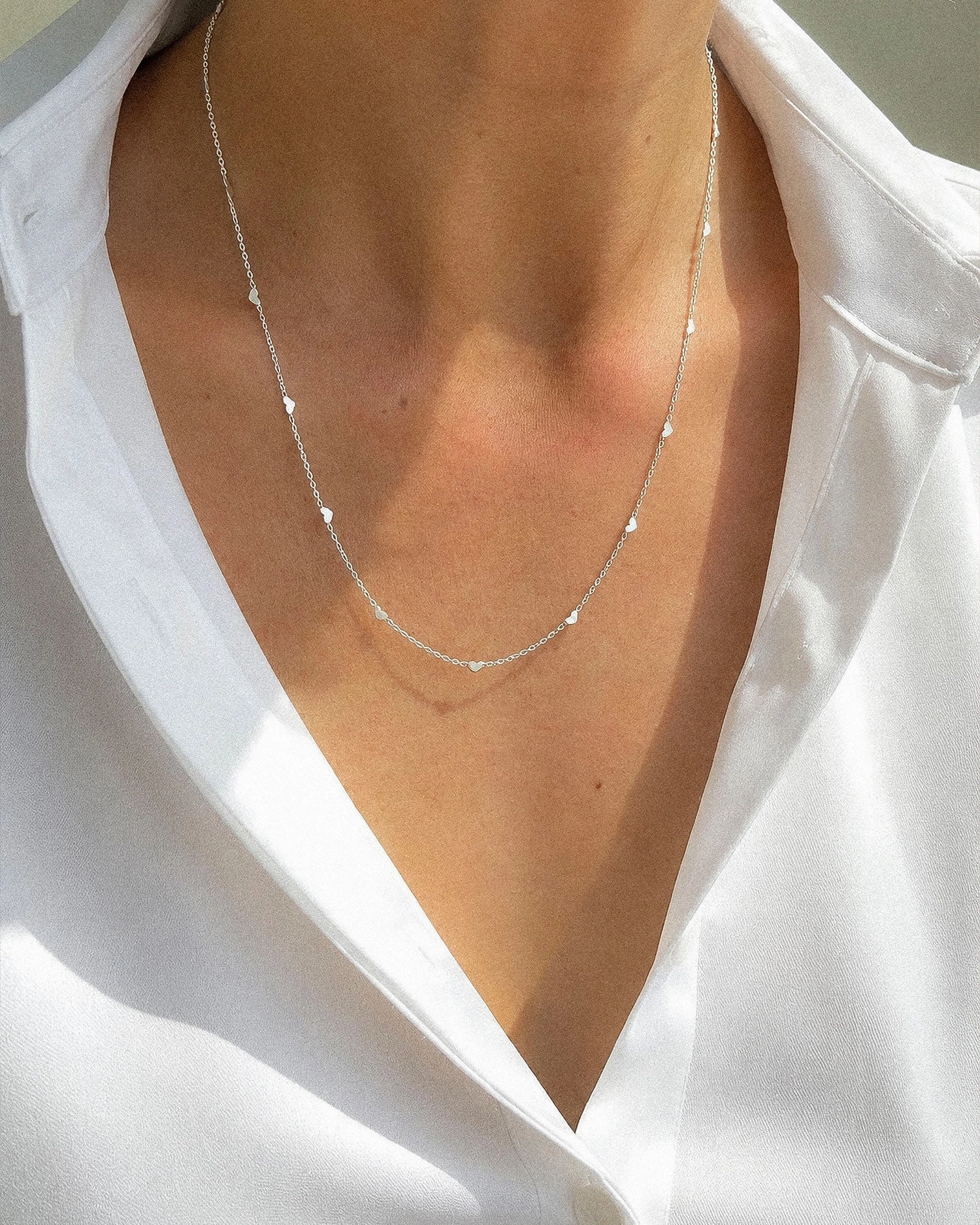 halsband i silver med små hjärtan längs en tunn kedja