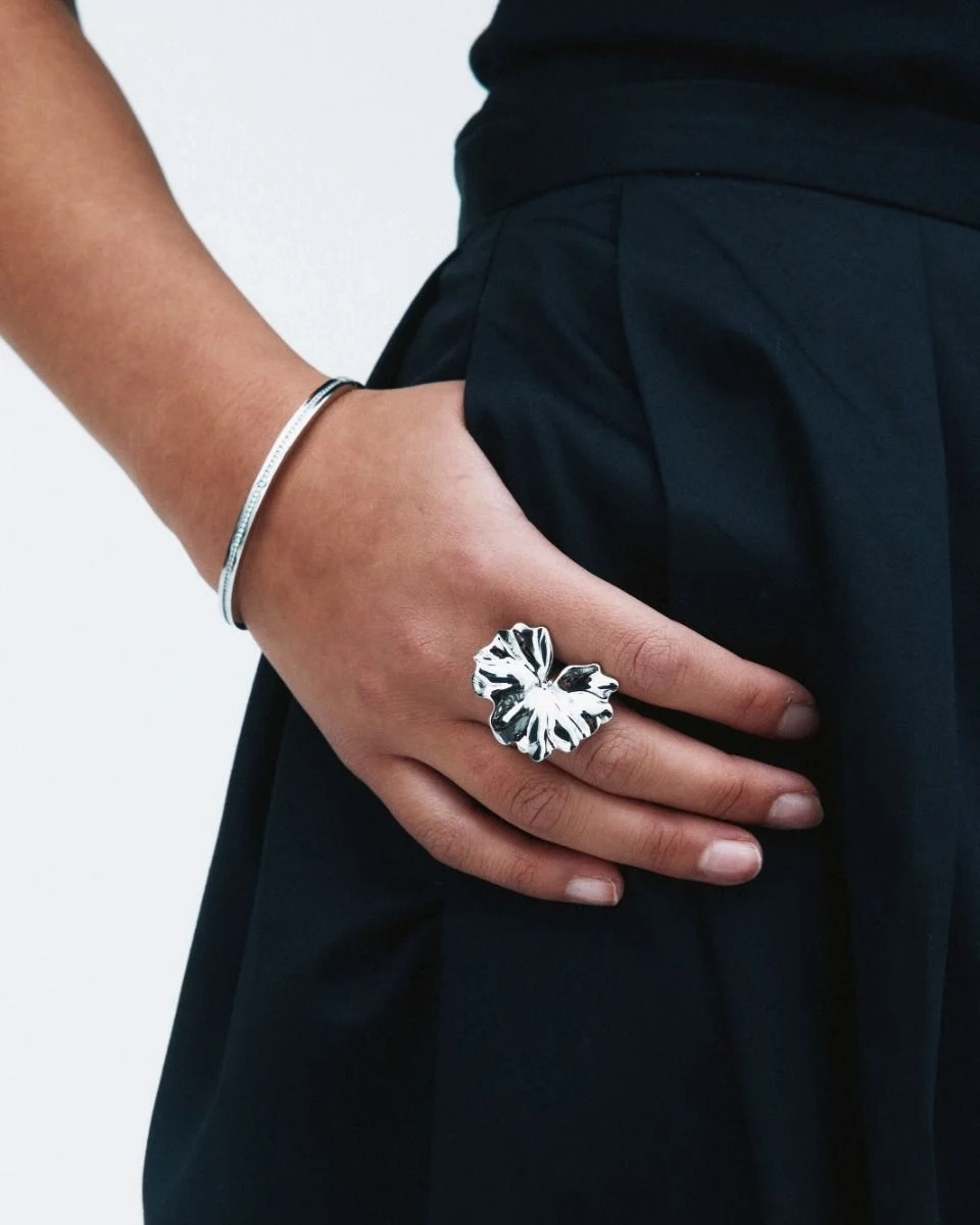 böljande blombladsformer som elegant breder ut sig över fingret.