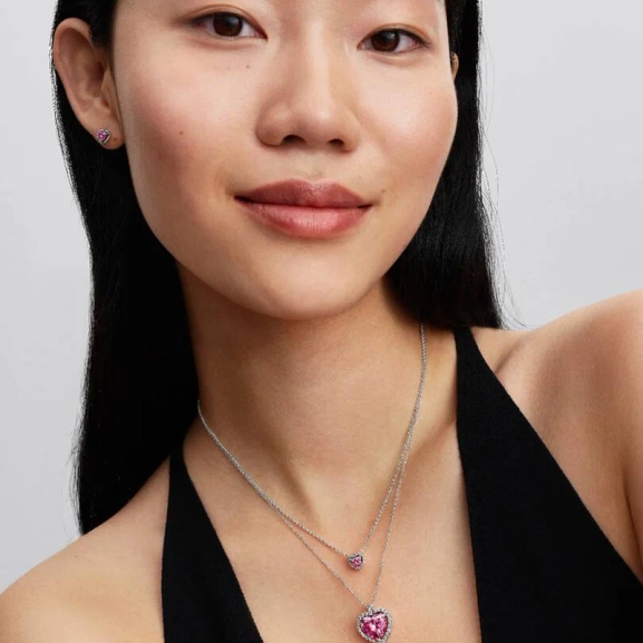 Rosa Sten Collierhalsband från Pandora. Ett hjärta av rosa kubisk zirkonia omringat av gnistrande stenar bildar en strålande cirkel som dansar längs kedjan och fångar ljuset i varje steg. Ett smycke som utstrålar elegans och romantik.
