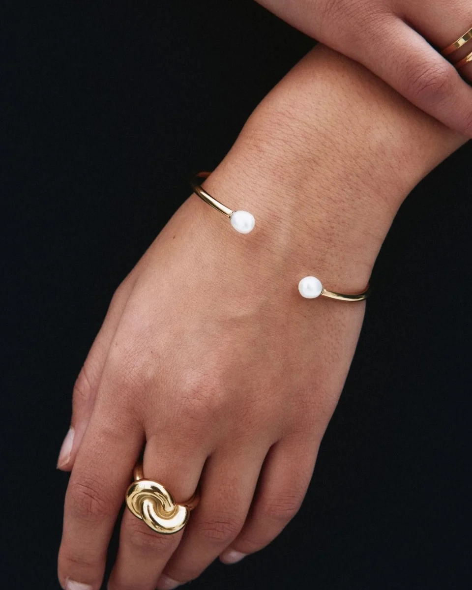 Guldfärgat öppet armband med två stora pärlor i ändarna