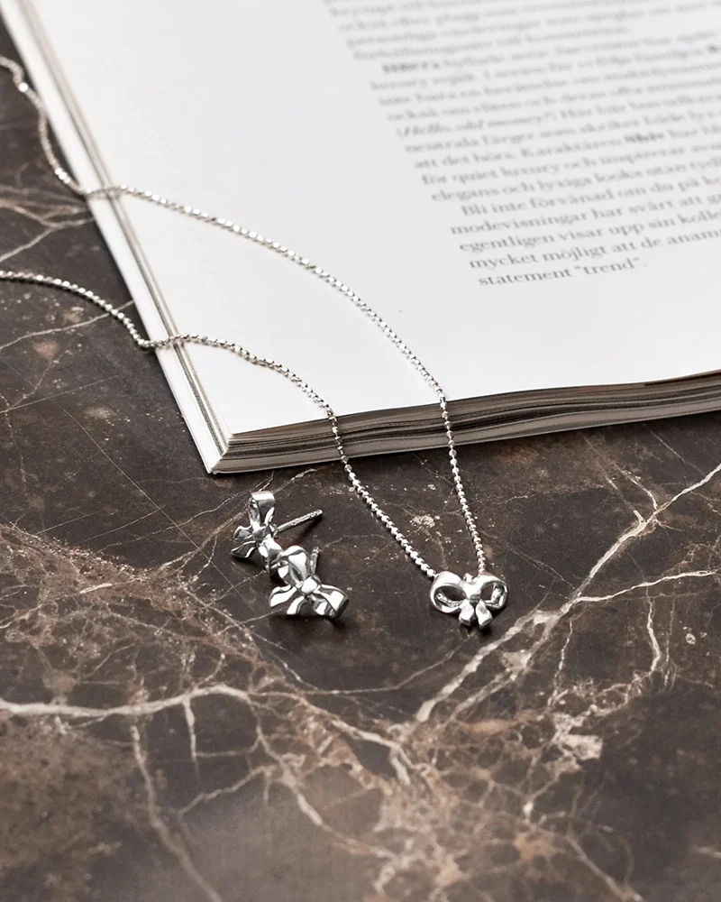 ett elegant halsband i återvunnet sterlingsilver med rosettberlock och gnistrande kedja