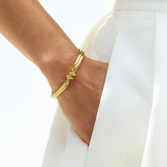 Guldpläterad bangle med spiralform och oval pärlemorpärla från Edblads Swivel-kollektion