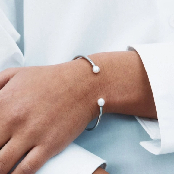 Armband i polerat rostfritt stål med öppen design och två pärlor i ändarna