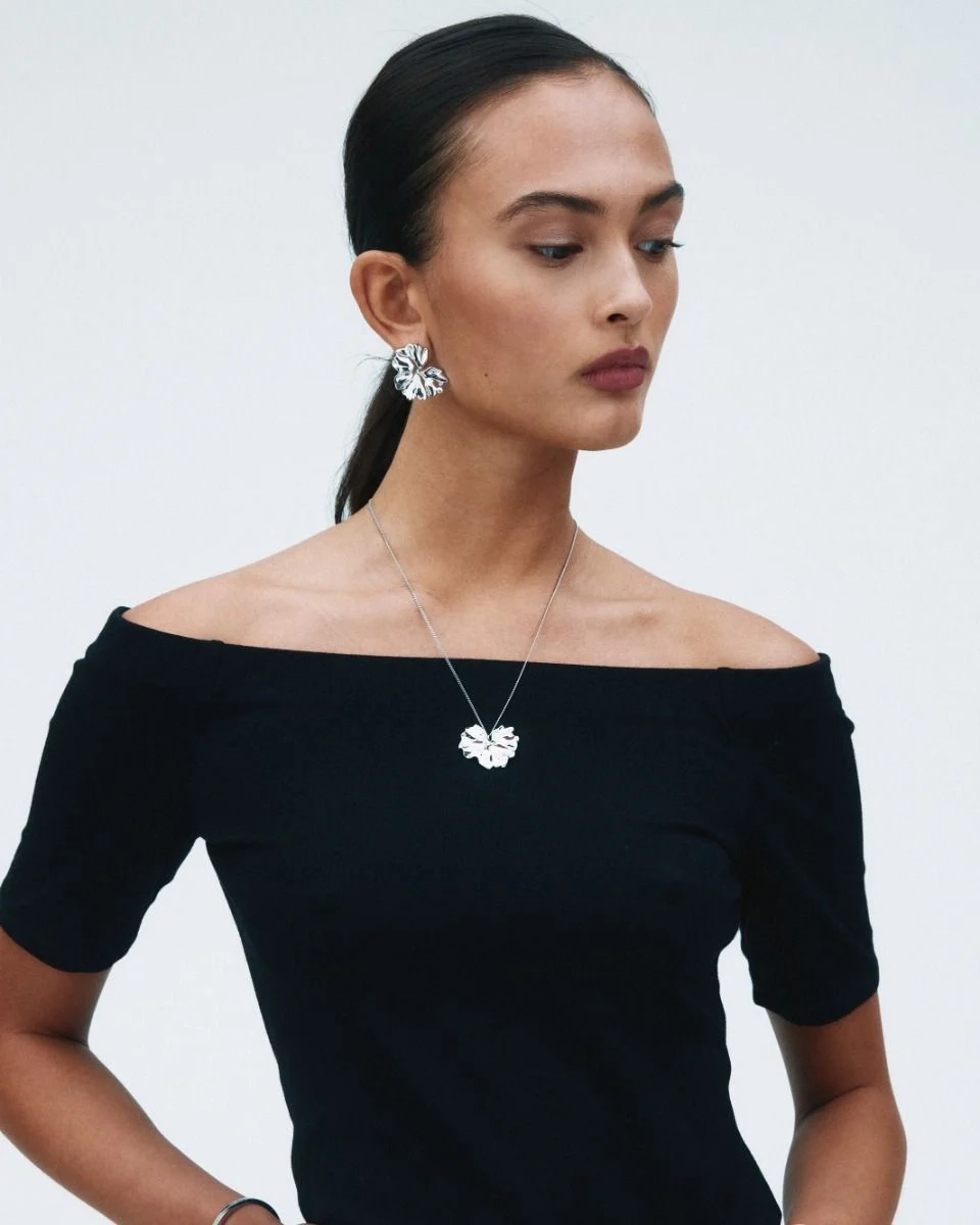 blanka örhängen i rostfritt stål med svepande blombladsform som elegant breder ut sig över örat.