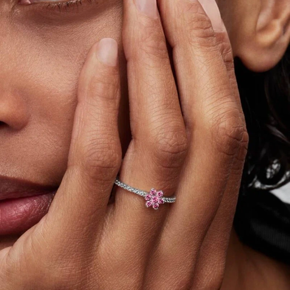 funkelnder Blumenring von Pandora aus Silber mit erhabener Blume und rosa Steinen auf einem halb funkelnden Ringband.