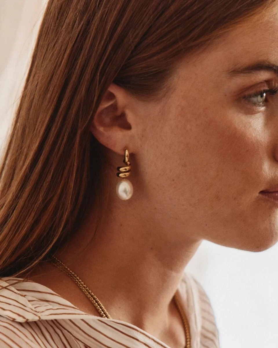 Större studsörhängen i 14K guldplätering med spiralform och oval pärlemorpärla från Edblad Swivel-kollektionen.