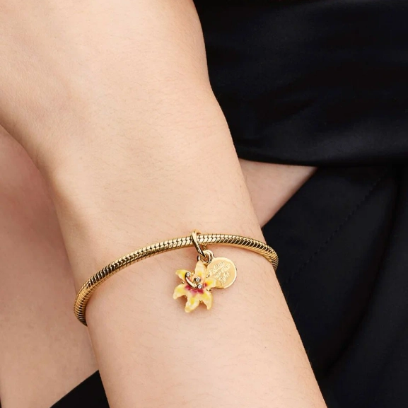 Disney Trassel Självlysande Solros Berlock Guld. Lys upp din stil med denna förtrollande berlock inspirerad av Disneys Törnrosa. Följ din egen väg med denna magiska ros som ger en subtil glöd till din look.