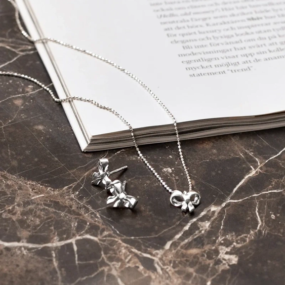 ett elegant halsband i återvunnet sterlingsilver med rosettberlock och gnistrande kedja