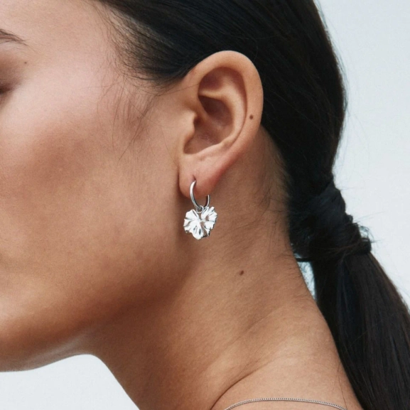 Hoops i polerat rostfritt stål med avtagbar charm som liknar ett stiliserat blomblad från Edblads Gerana-serie.