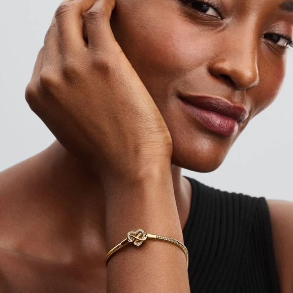Pandora Moments Glittrande Ormkedjearmband med Hjärtlås Guld. Smyckat med stenar och ingraverat med "Family forever and always". En symbol för evighet och familjeband.