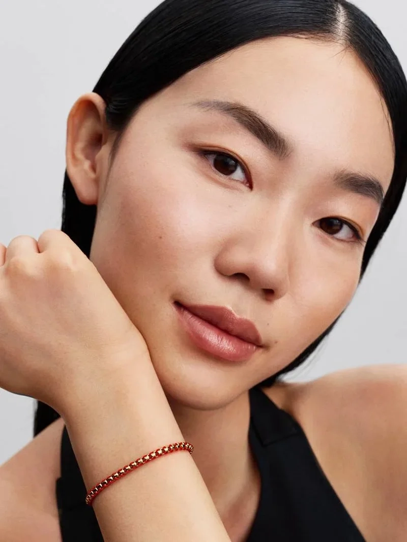 Flätat armband med röd tygdetalj i guld från Pandora Moments. Skapa en glamorös stil med detta elegant designade armband i 14 karat guldplätering och livligt rött textilsnöre.