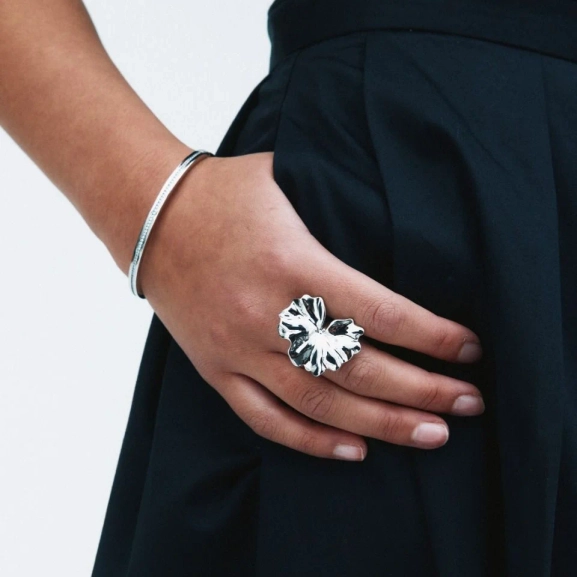 böljande blombladsformer som elegant breder ut sig över fingret.