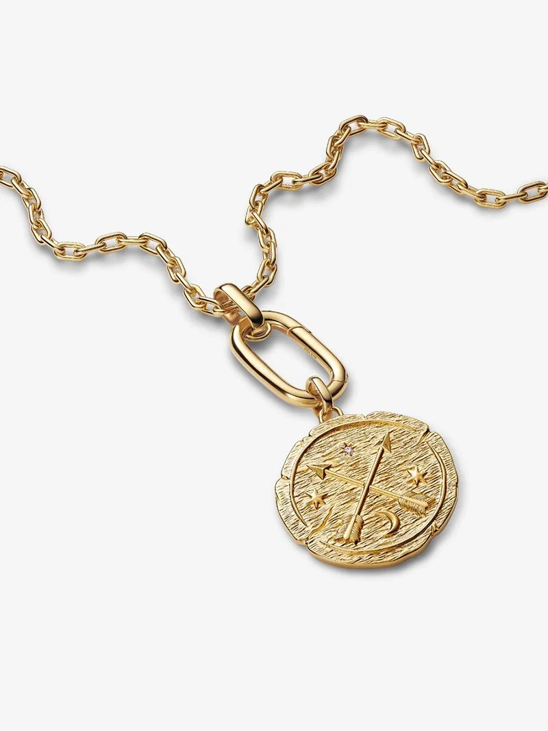 Medaljong Korsande Pilar Berlock Guld. Symbol för att sträva mot det bättre. Tillverkad av 14 karat guldplätering med korsade pilar och latinska frasen "AD MELIORA". En påminnelse om att följa din inre kompass och leva efter dina värderingar.