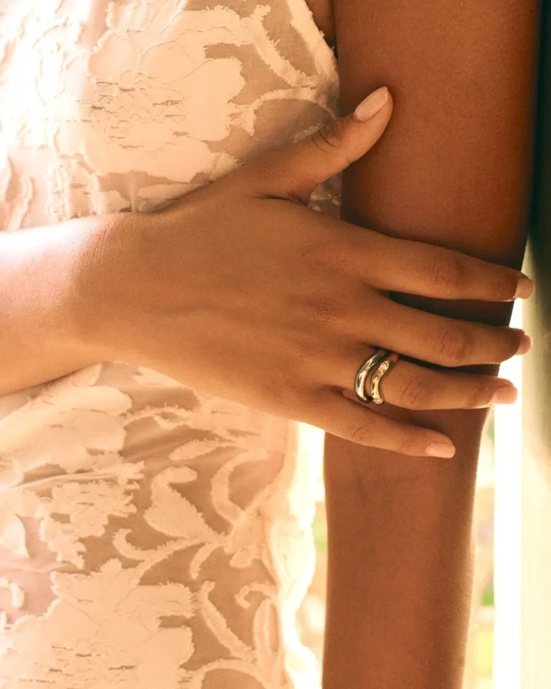 Två släta Selena-ringar i stål och guld med vågformade skenor från Edblad