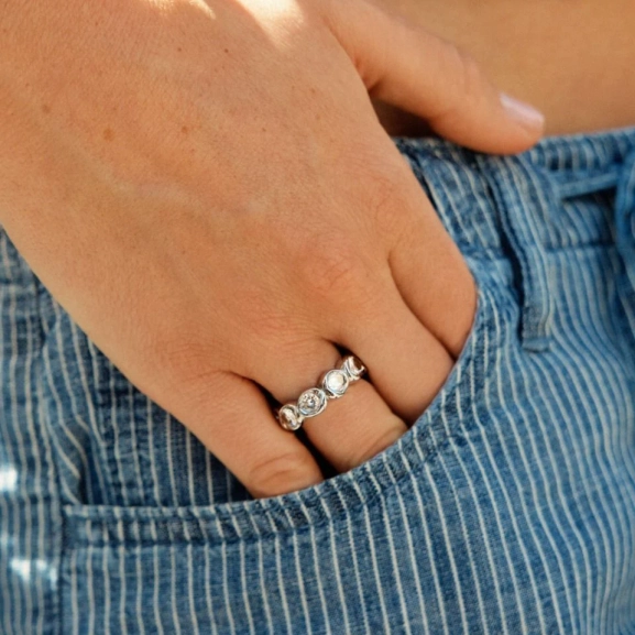 Ring i blankt rostfritt stål med gnistrande stenar runt hela skenan och mjukt rundad insida