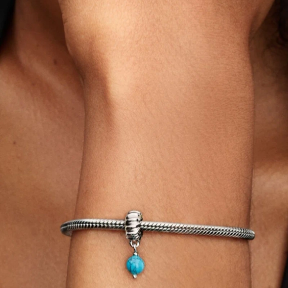 Turkosfärgad hängberlock från Pandora Moments i sterlingsilver. Unik struktur med rund turkosfärgad berlock. Lekfull uppfräschning av din stil.