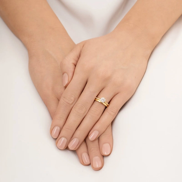 ring i 18K gult guld med en stor briljantslipad diamant och mindre pavédiamanter längs skenan.