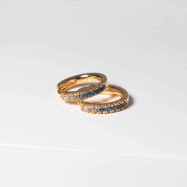 Ellera Medio Örhängen Blå Guld från Sif Jakobs i 18K guldpläterat silver med gnistrande Cubic Zirconia-stenar.