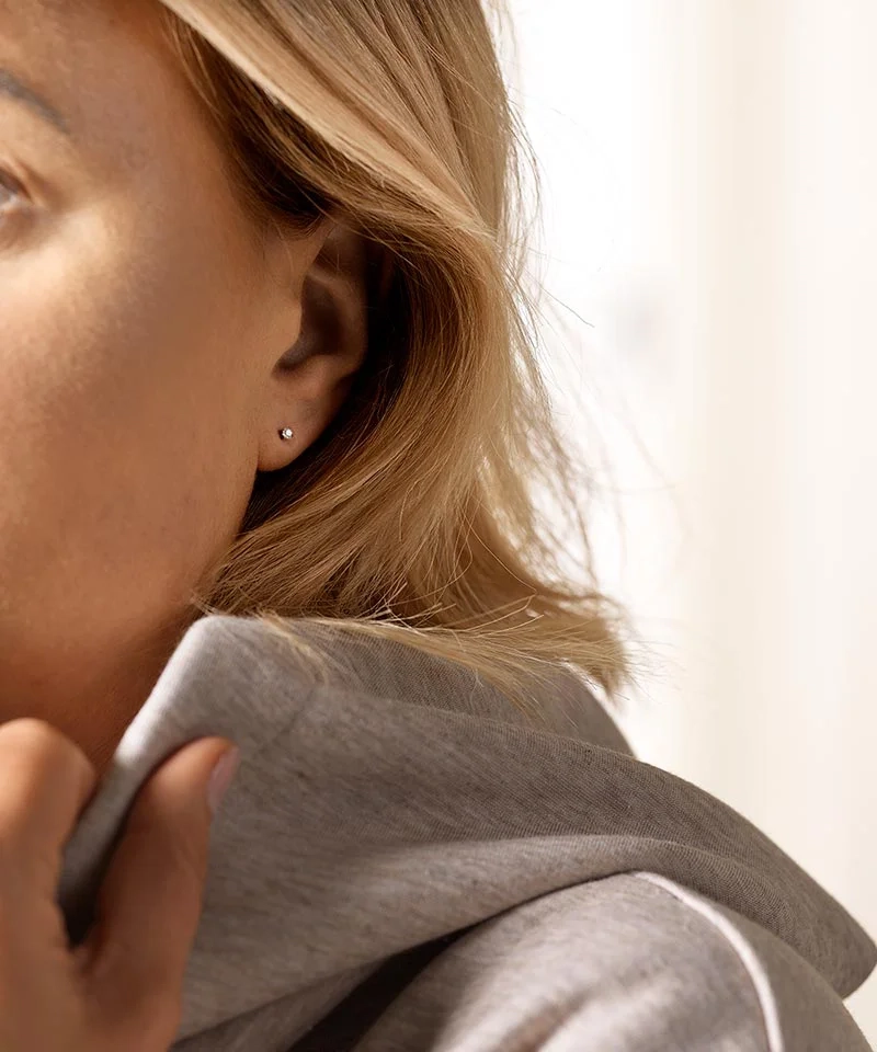 Små vita Blomdahl-örhängen i medicinsk titan med 3 mm cubic zirconia-sten.