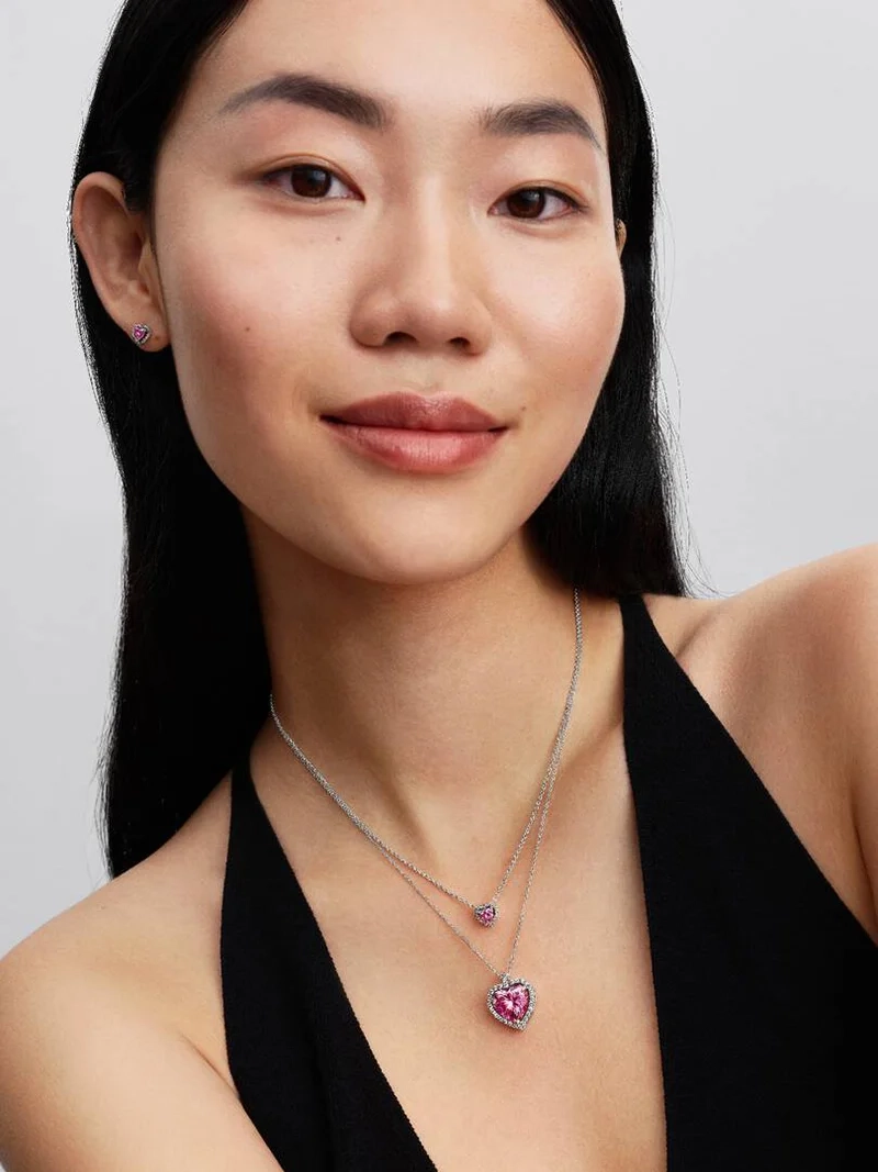 Rosa Sten Collierhalsband från Pandora. Ett hjärta av rosa kubisk zirkonia omringat av gnistrande stenar bildar en strålande cirkel som dansar längs kedjan och fångar ljuset i varje steg. Ett smycke som utstrålar elegans och romantik.