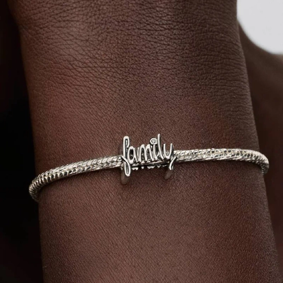 jossa on käsin kirjoitettu sana "family" ja kimalteleva kuutiollinen zirkonia "i"-kirjaimen yläpuolella. Rakkauden ja yhdessäolon symboli Pandora Moments -mallistosta.