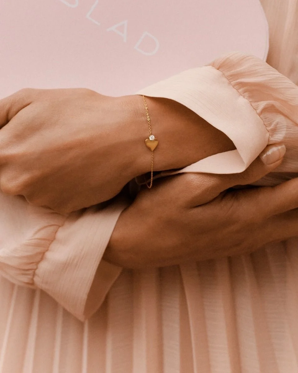 Armband i 14K guldplätering med fasettslipad kedja och stilrent hjärta prytt av en liten gnistrande sten.