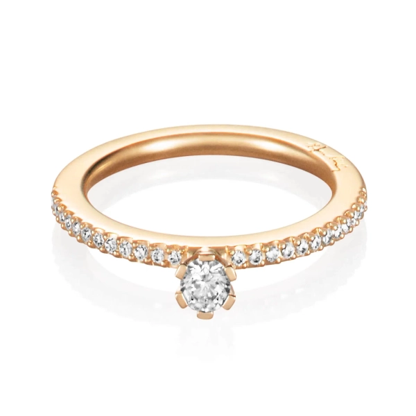 tunn ring i 18K gult guld med en större briljantslipad diamant och små pavédiamanter längs skenan.