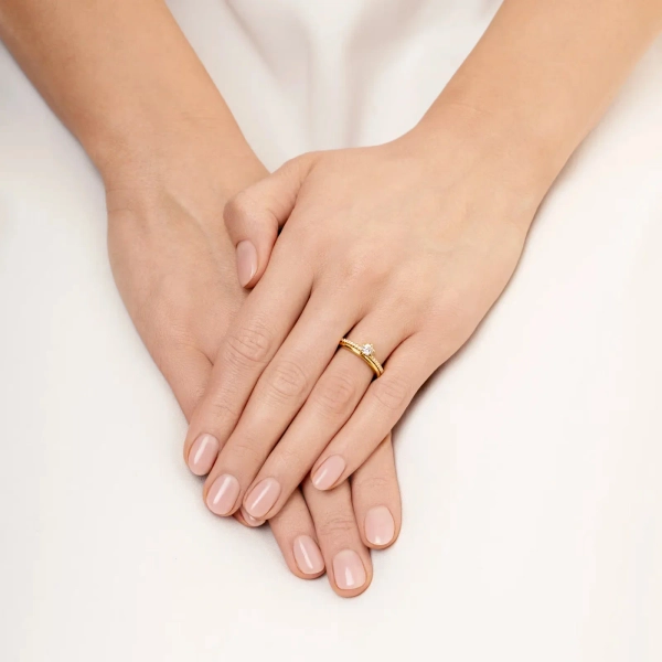 smal ring i 18K gult guld med en större briljantslipad diamant och mindre pavédiamanter på skenan.